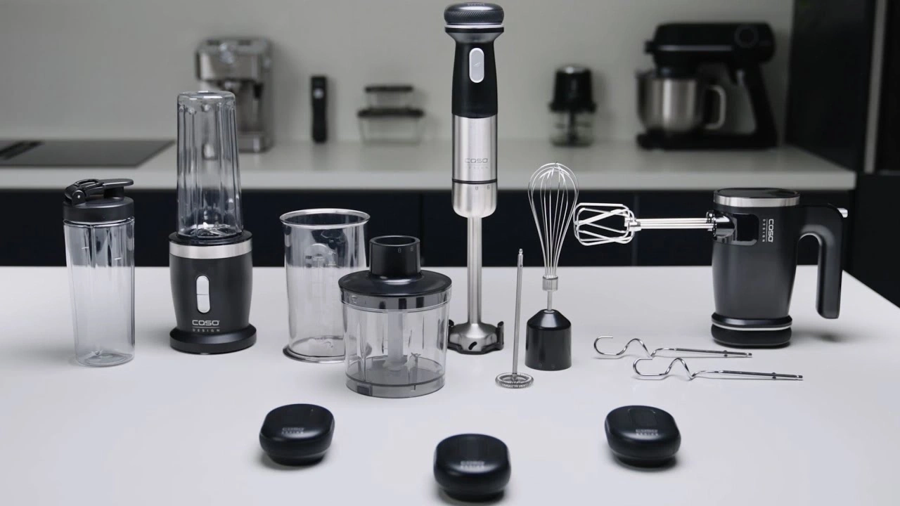 Küchengeräte auf weißem Tisch: Mixer, Stabmixer, Schneebesen, Handmixer, Zubehör.