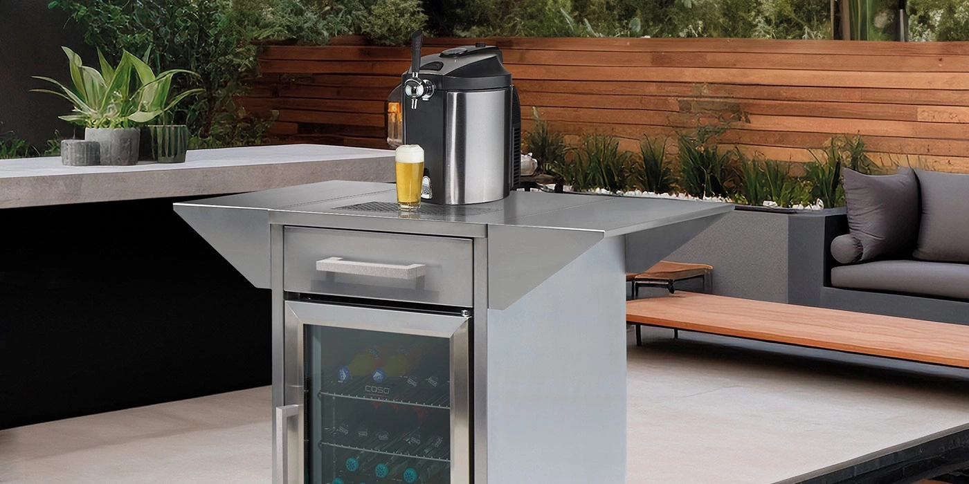 Bierkühler mit Zapfhahn und Glas auf einer Terrasse im Freien