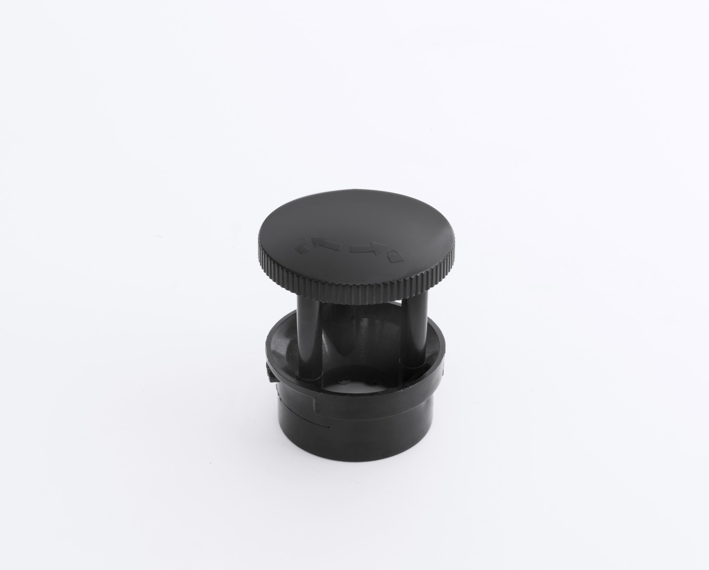 Black plastic cap with arrows and ridges on a white background, isolated