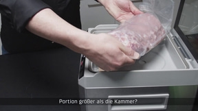 Person legt Fleisch in Vakuumiergerät. Portion zu groß für die Kammer?