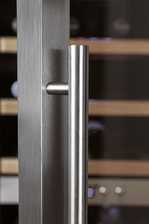 Close-up of a stainless steel handle on a refrigerator door, vertical lines, modern design