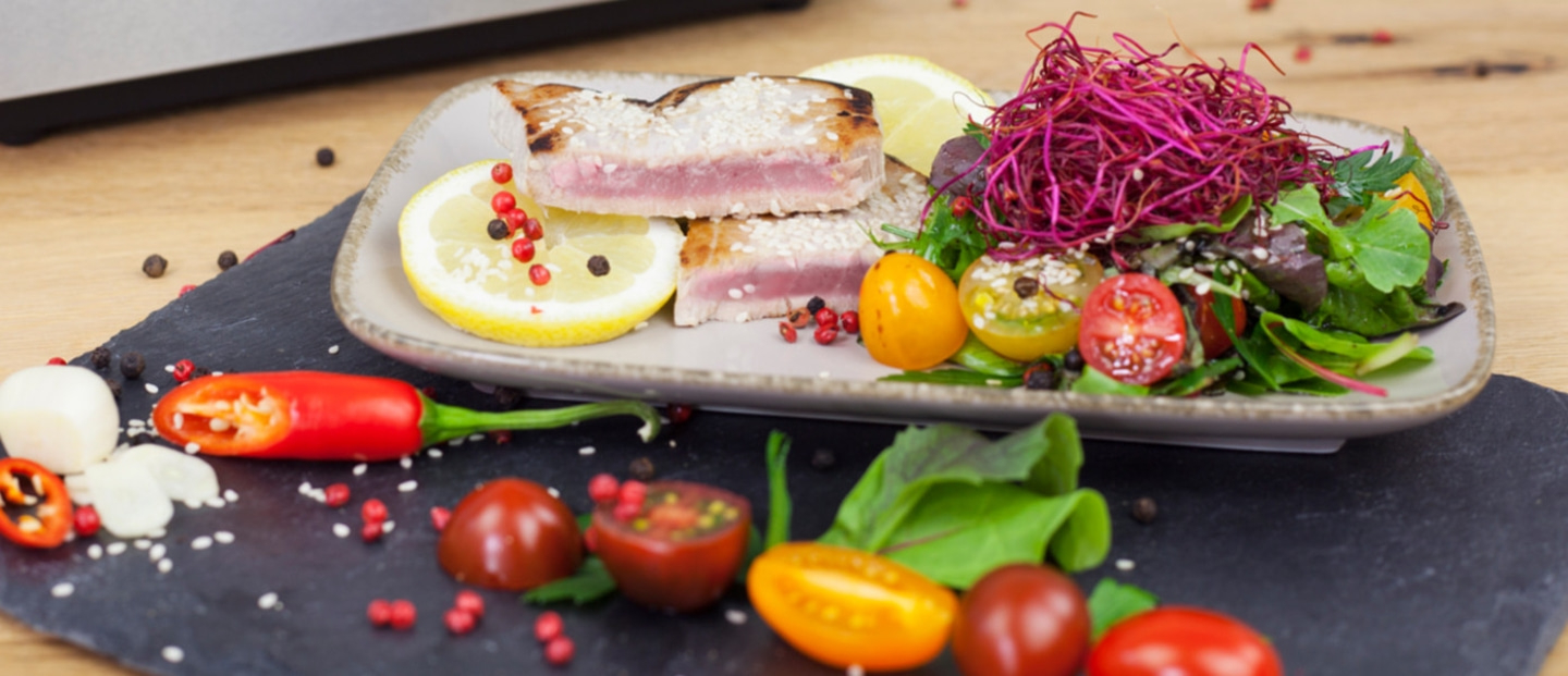 Gebratenes Thunfischsteak mit Salat, Tomaten und Zitrone auf einem Teller