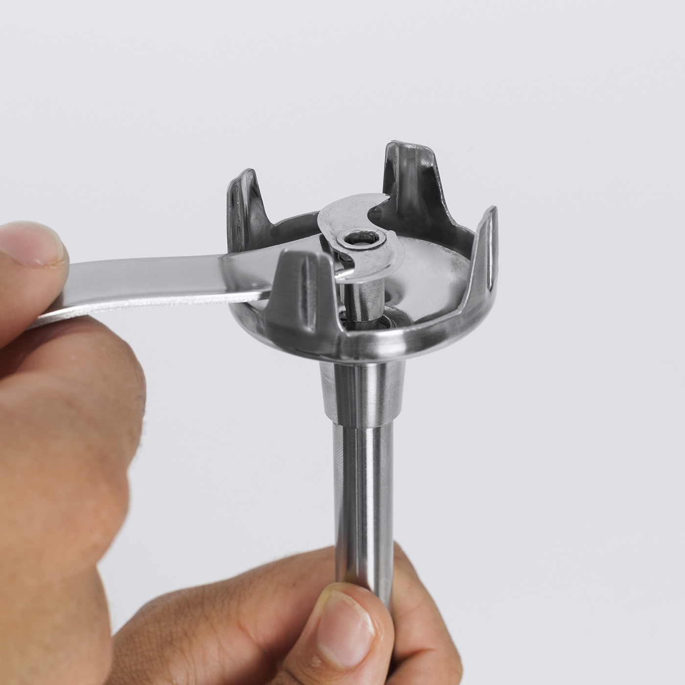 Nahaufnahme eines silbernen Mixers, der von einer Hand gehalten wird, mit Werkzeug.