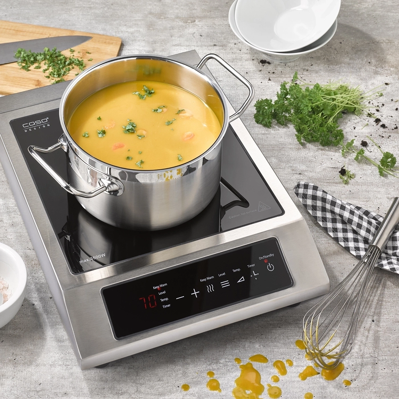 A pot of soup on an induction cooktop with kitchen utensils.