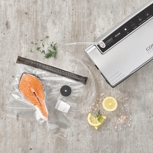 Salmon fillet in vacuum bag with lemon and herbs on gray background