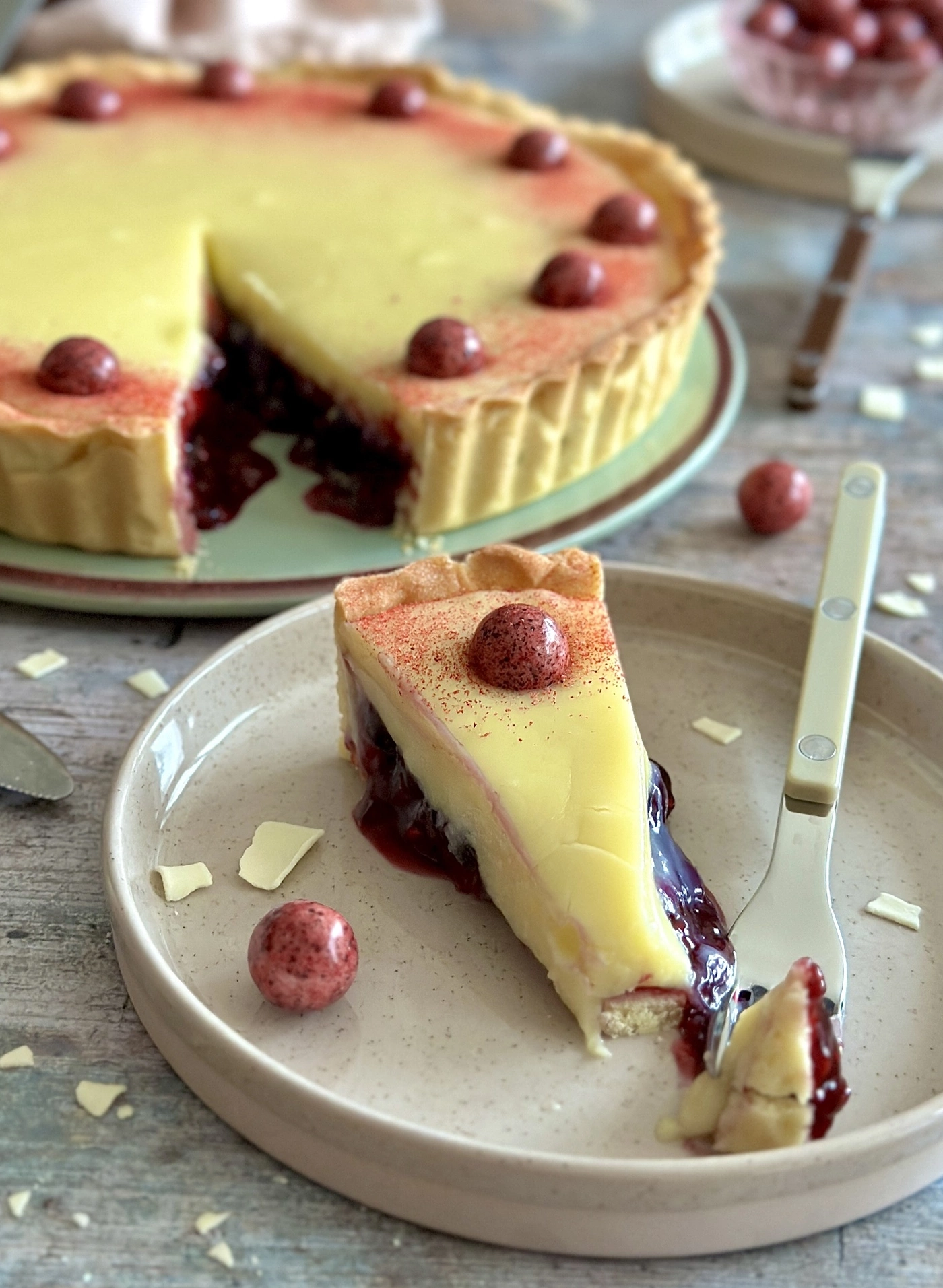 Ein Stück Kirsch-Zitronen-Tarte mit roten Beeren und Puderzucker.