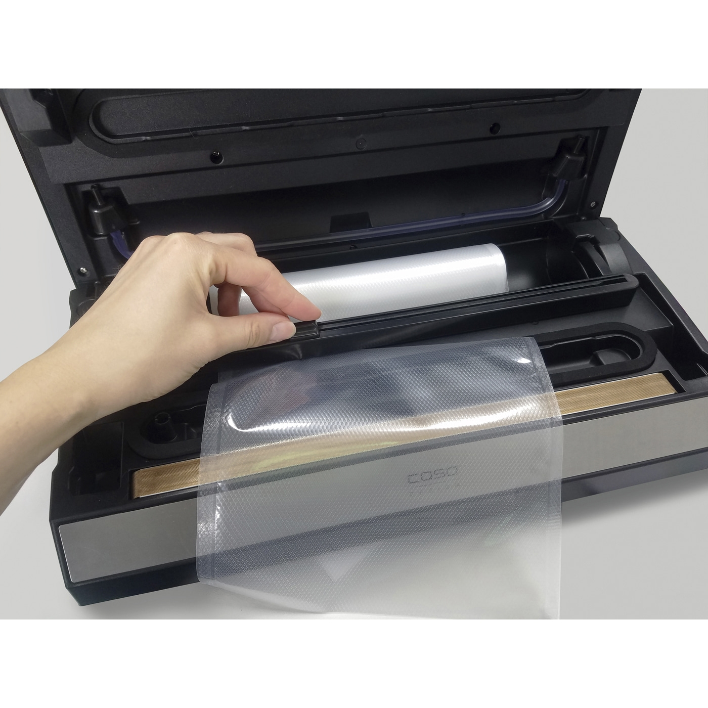 Hand legt Folie in Vakuumiergerät, um Lebensmittel zu verpacken.