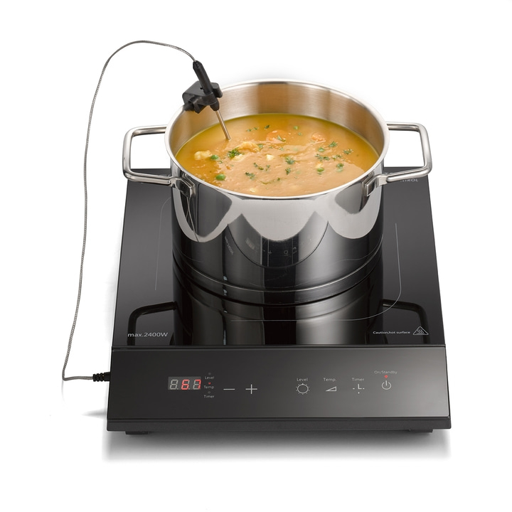 Soup pot on induction cooktop with temperature probe and control panel, cooking.