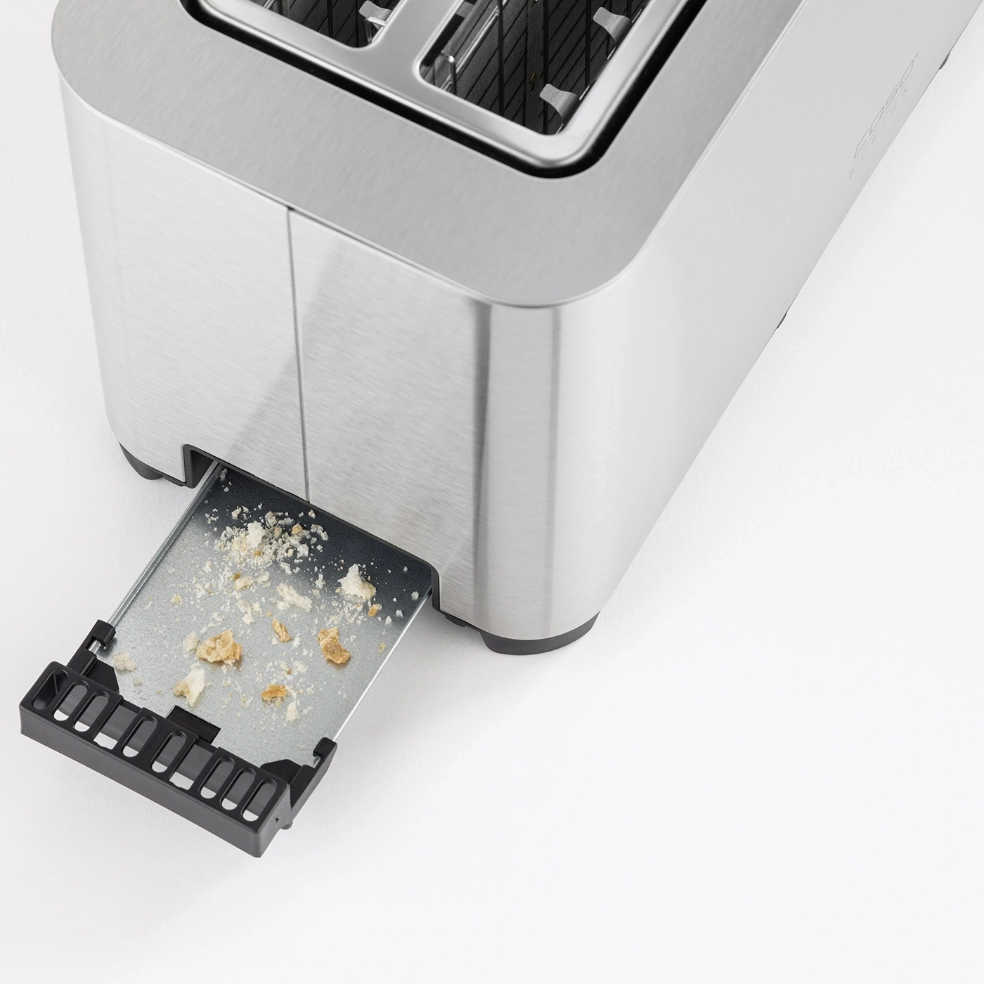 Toaster mit herausgezogener Krümelschublade und Brotkrümeln auf weißem Hintergrund