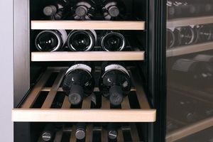 Wine cooler with multiple bottles, wooden shelves, and a glass front.
