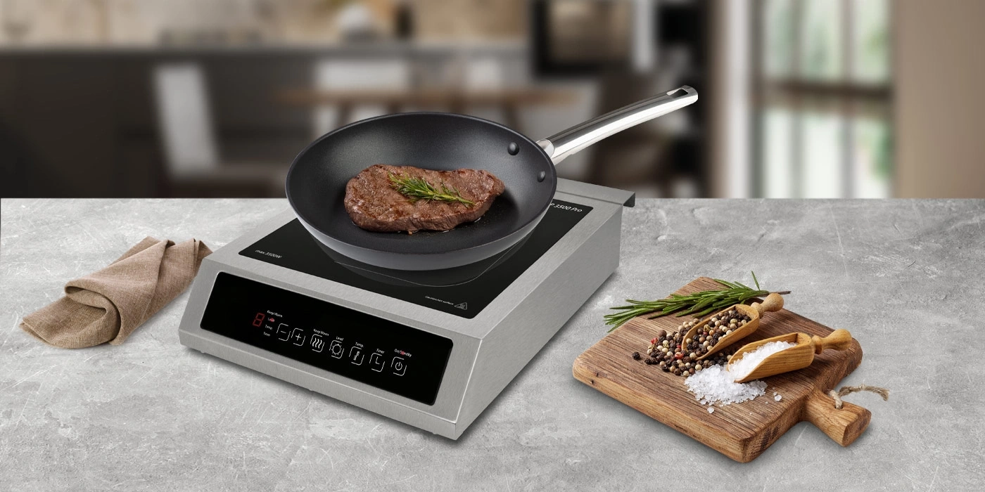 Ein Steak brät in einer Pfanne auf einem Induktionskochfeld mit Gewürzen.