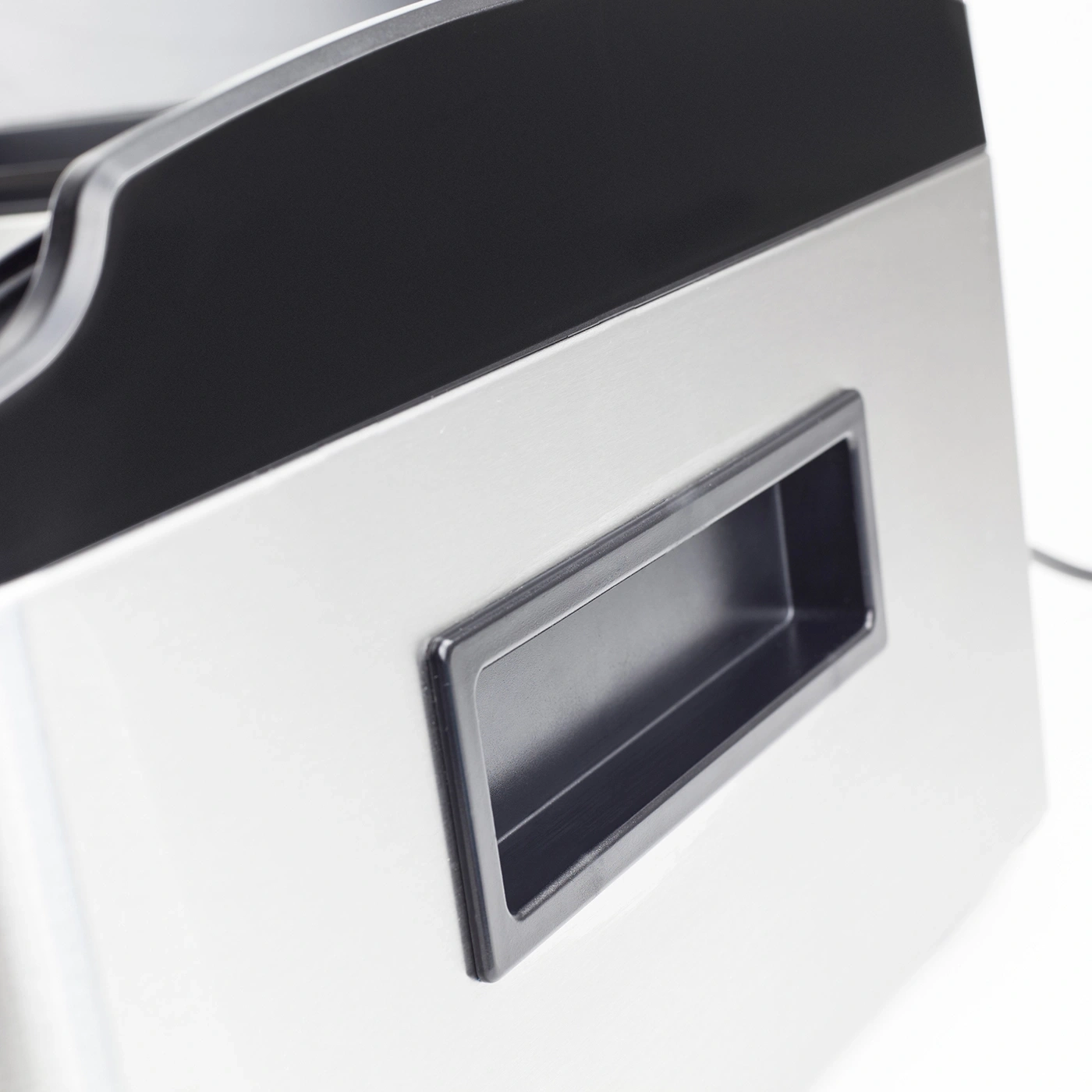 Close-up of a silver appliance with a black handle and black top.