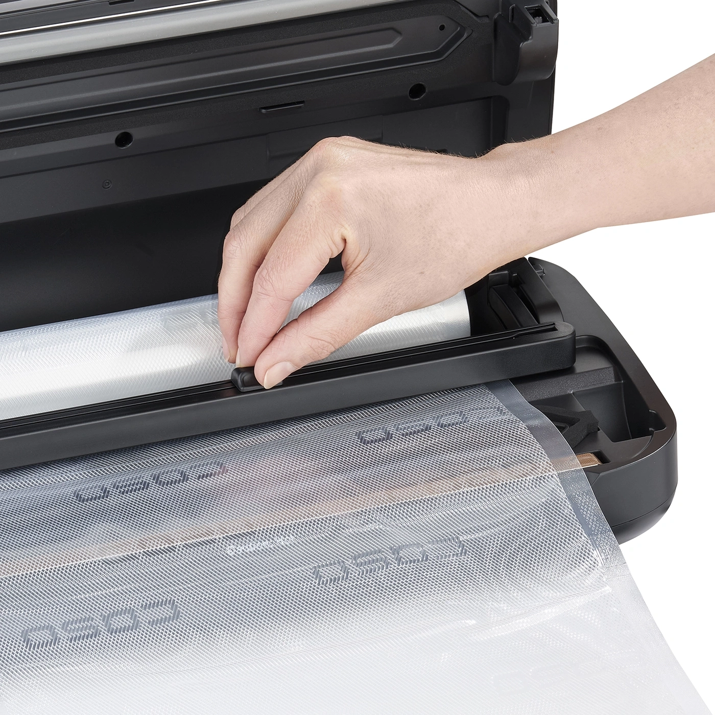 Main actionnant une scelleuse sous vide, insérant un film, gros plan, noir
