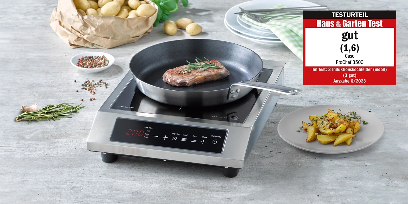 A steak is being fried on an induction hob, with potatoes next to it.