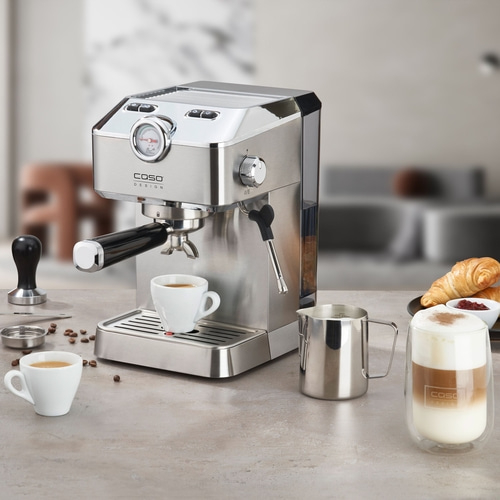 Espressomaschine beim Frühstück mit frischem Kaffee, Cappuccino und Croissants