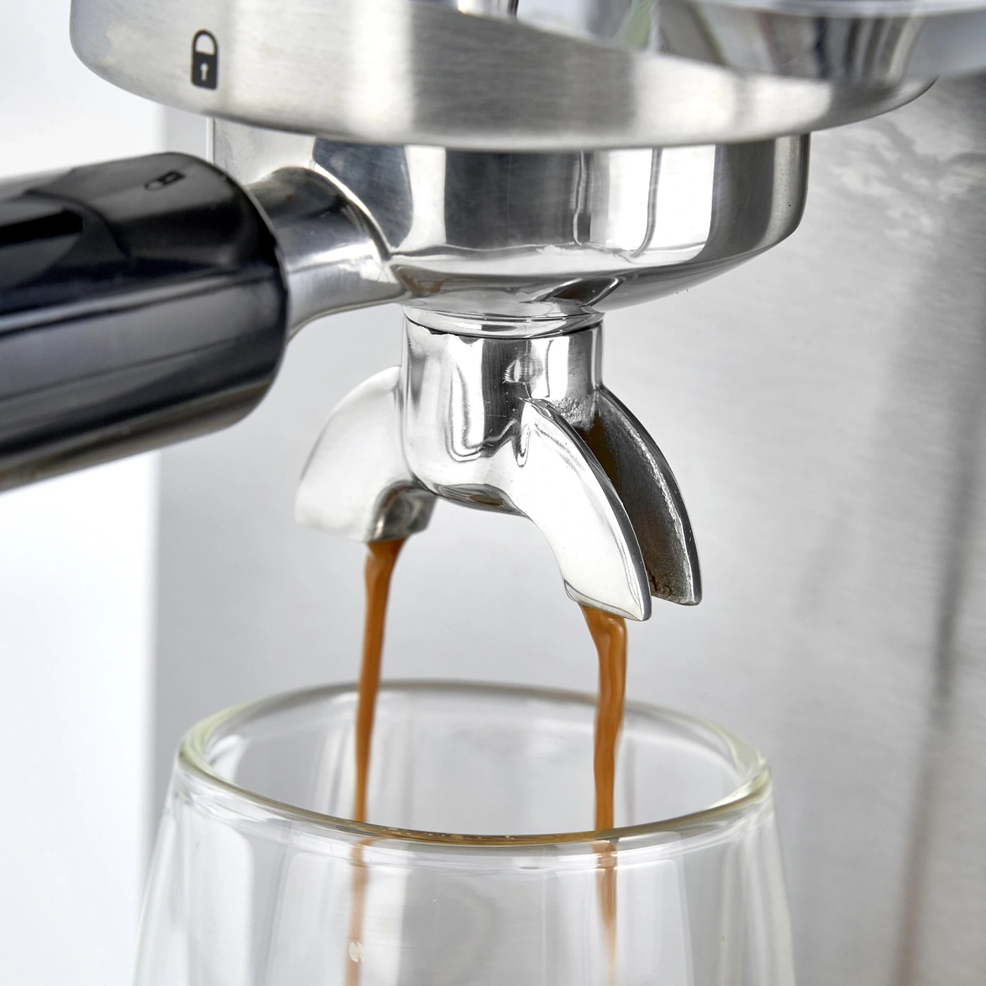 Nahaufnahme einer Espressomaschine, die Kaffee in ein Glas gießt. Edelstahl, Getränk.