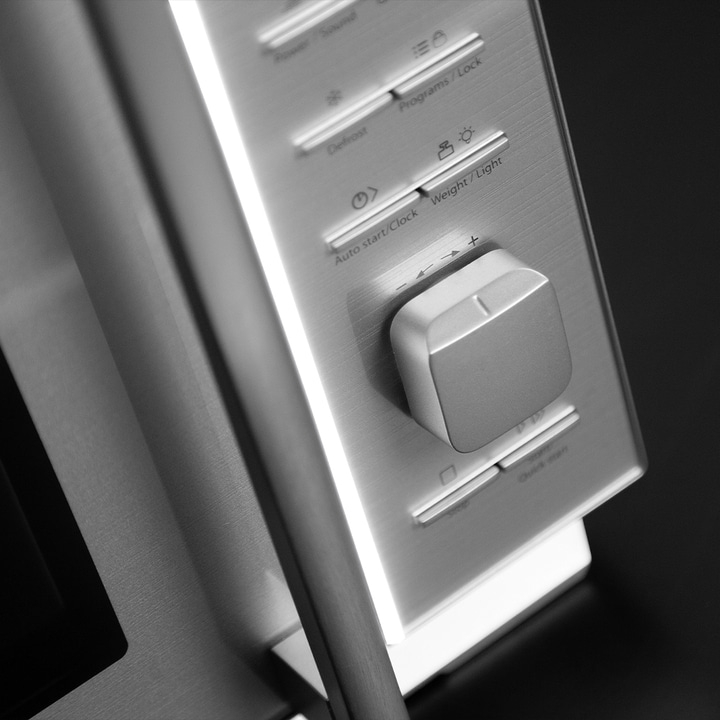 Close-up of a microwave control panel with buttons and controls, gray color