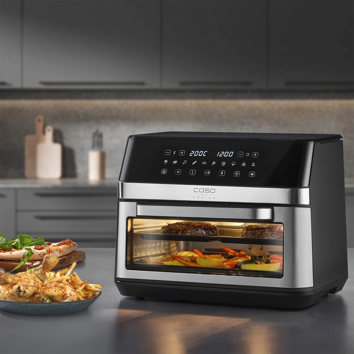 Friteuse à air avec nourriture, pizza, poulet et frites sur la table.