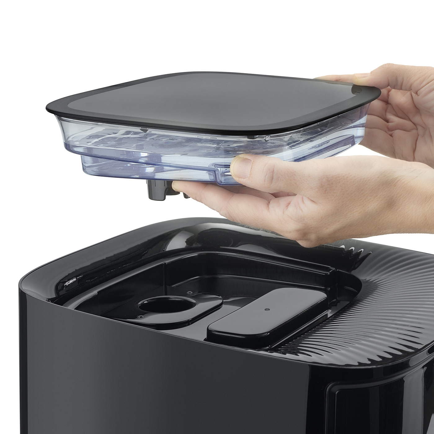 Person holding a black container over another black container, close up.