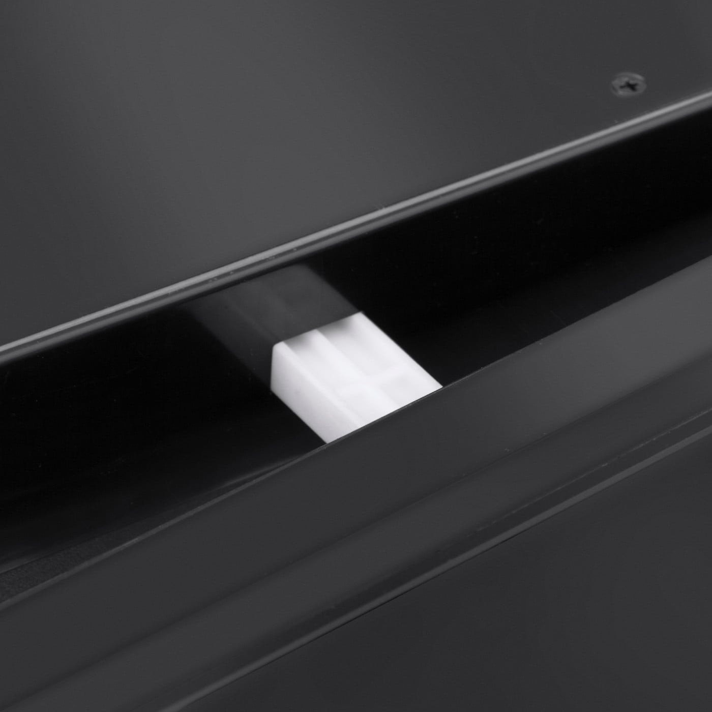 Close-up of a black object with a white plug in a recess, detail shot